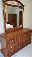 Frontal view of the wooden dresser with the attached mirror, showing drawer configuration and mirror frame detail.