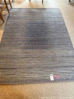 Full view of Threshold brand blue tone woven area rug spread out on floor, showing horizontal striped pattern in mixed blue tones.