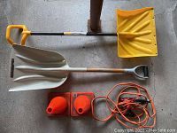 Two shovels, two orange traffic cones, and one set of jumper cables