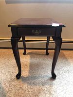 Front view of the dark wood side table showing drawer and curved legs