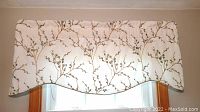 Front view of scalloped valance with floral branch embroidered pattern on fabric over window