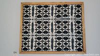 Full view of the wood framed batik style textile art showing the geometric pattern and wooden frame.
