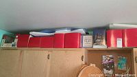 Top shelf view showing ten boxes of Christmas Village figures in red boxes along with some original branded boxes.