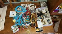 Overview of assorted jewelry items spread on wooden table including necklaces, bracelets, watches, earrings and pins