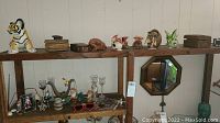Two wooden shelves with various decorative items including dragon figurines, wooden lidded containers, ceramic pelican, antique wooden box, and small collectibles arranged.