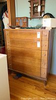 Front view of highboy dresser showing five-drawer configuration, ribbed fronts, brass-tone handles and overall condition