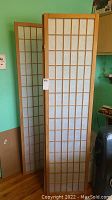 Front view of the three panel room divider showing wood grid design and translucent panels.