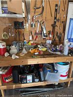 Full view of garage workbench with assorted hand tools, containers, and pegboard with mounted tools.