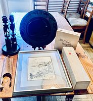 Photo of wooden elephant candle holders, decorative plate on stand, framed art print on table, and two wooden boxes