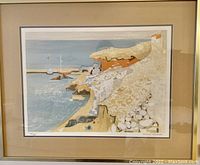 Framed coastal landscape print by George Lambert, signed and numbered edition 124/250, showing detailed cliffs, sea, boats, and buildings in muted colors.
