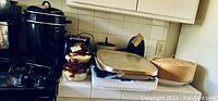 Wide view of pots, pans, toaster, and other kitchen items on kitchen counter.