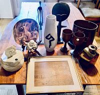 Photo showing all items on a wooden table including vases, wood goblets, statues, framed artwork, decorative plate and containers.
