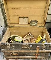 Vintage wooden storage trunk open showing baskets, garden tools, and other small containers inside