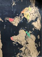 Photo of partially scratched world map showing continents and countries with bright color reveals on dark background.