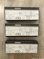 Three unopened Original Vola boxes labeled DESIGN with line drawings of faucet components