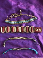 Photo of four bracelets laid on purple fabric, showing variety of styles and colors