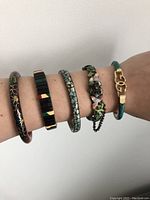Five assorted retro bangles shown on wrist from top view, displaying varied patterns and colors.