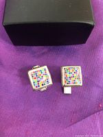Pair of pastel color blocked square cufflinks on purple background
