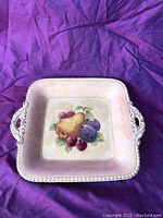 Top view of the square ceramic tray showing fruit design and decorative handles.