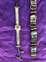 Two antique bracelets displayed on purple cloth background, showing detailed design and clasp mechanisms.