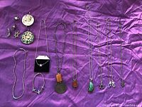 Full view of assorted boho jewelry on purple fabric: multiple necklaces with various pendants, earrings, and bracelets.