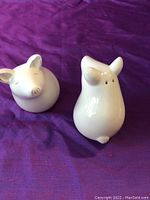 Two white ceramic mouse salt and pepper shakers, one upright and one resting on its side showing details