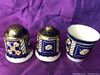 Front view of salt shaker, pepper shaker, and salt pig showing floral hand-painted details in blue, white, and gold.