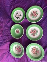 Overview of all 6 pieces showing varied plate and bowl sizes and floral pattern with green rim.