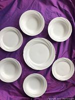 Overview of all items showing the plates, bowls, and large platter in white porcelain with embossed ridge design.