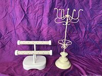 Two jewelry stands: a dual-tier fabric-covered bracelet holder and a cream metal necklace holder with hooks and ring holder.
