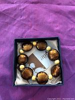 Murano glass brown and gold stretch bracelet in open box, showing the large round brown glass beads with gold foil and smaller textured golden spacer beads.