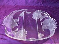 Clear glass divided relish tray with floral etching and three sections, viewed from above on purple fabric.