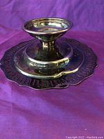 Photo of the silver antique ornate candlestick showing the round base and decorative edge.