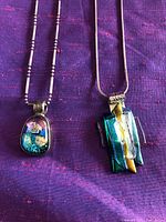 Close-up of two Murano glass pendants with sterling silver bails, showing detailed colors and 925 stamp on bail.