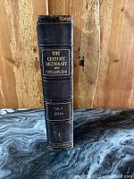 Spine of the antique hardcover book showing the title 'The Century Dictionary and Cyclopedia Vol. X Atlas' embossed in gold on black leather.