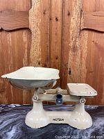 Front view of the cream colored antique Weylux The Queen weigh scale with large weigh tray and balance plate on a wooden background.