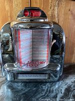 Front view of the jukebox-style radio tape player showing the glass panel with music selections and chrome casing.