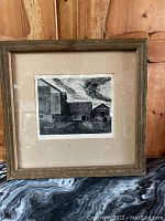 Full view of the framed etching inside a rustic wooden frame with visible wood grain.