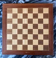 Full view of mahogany checkerboard with alternating wood squares and decorative border.