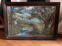 Full view of framed painting depicting a landscape with castle, river, and trees.