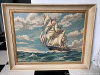 Full view of the framed painting showing a large sailing ship against a cloudy sky and choppy ocean waves.