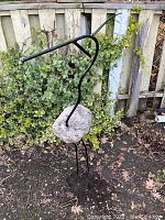 Full view of the bird garden sculpture showing stone body and iron rod neck, legs, and beak.
