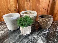 Photo of all four pots grouped on a marble surface with wooden wall background showing size and texture differences.