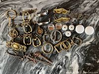 Full view of the lot showing variety of brass and metal hardware pieces on a marbled surface.