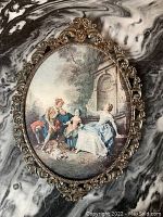 Front view of the oval print featuring classical Italian figures and surrounding ornate metal frame.