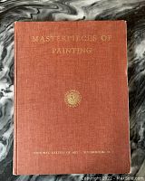 Brown hardcover book with gold embossed text 'Masterpieces of Painting' and 'National Gallery of Art Washington D.C.' on cover laid on marbled surface.