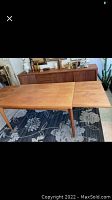 Full view of teak dining table with one leaf extended