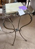 Full view photo of antique marble top plant stand showing metal base and marble top.
