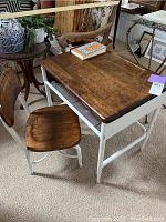 Child's antique school desk showing wood top, white metal frame, and vintage book on top