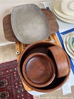 Three wooden bowls nested inside each other atop the wooden carving board, with two metal platters underneath.